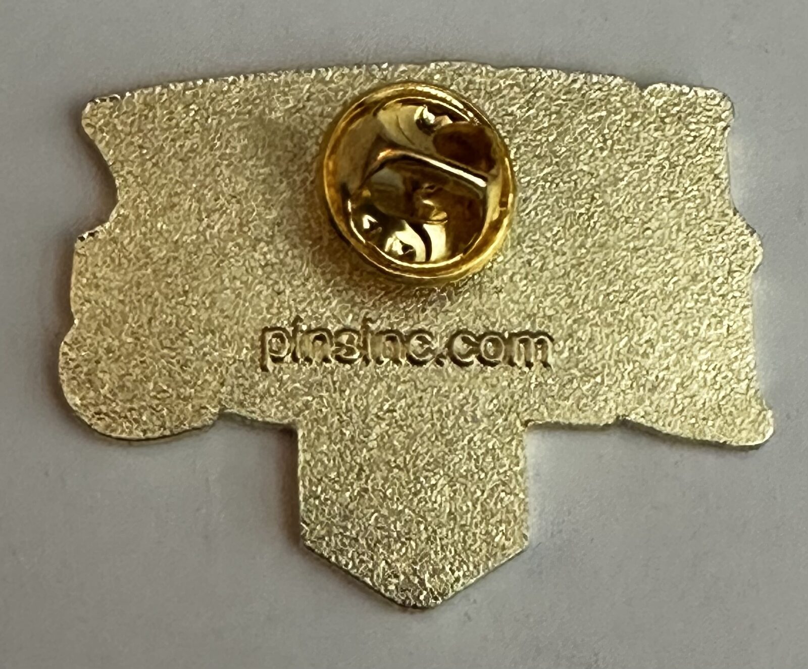 Back of the Mighty Deeds enamel pin showing the pin clasp